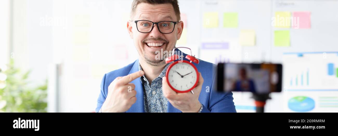 Ritratto di un uomo d'affari sorridente che tiene in mano la sveglia rossa mano Foto Stock