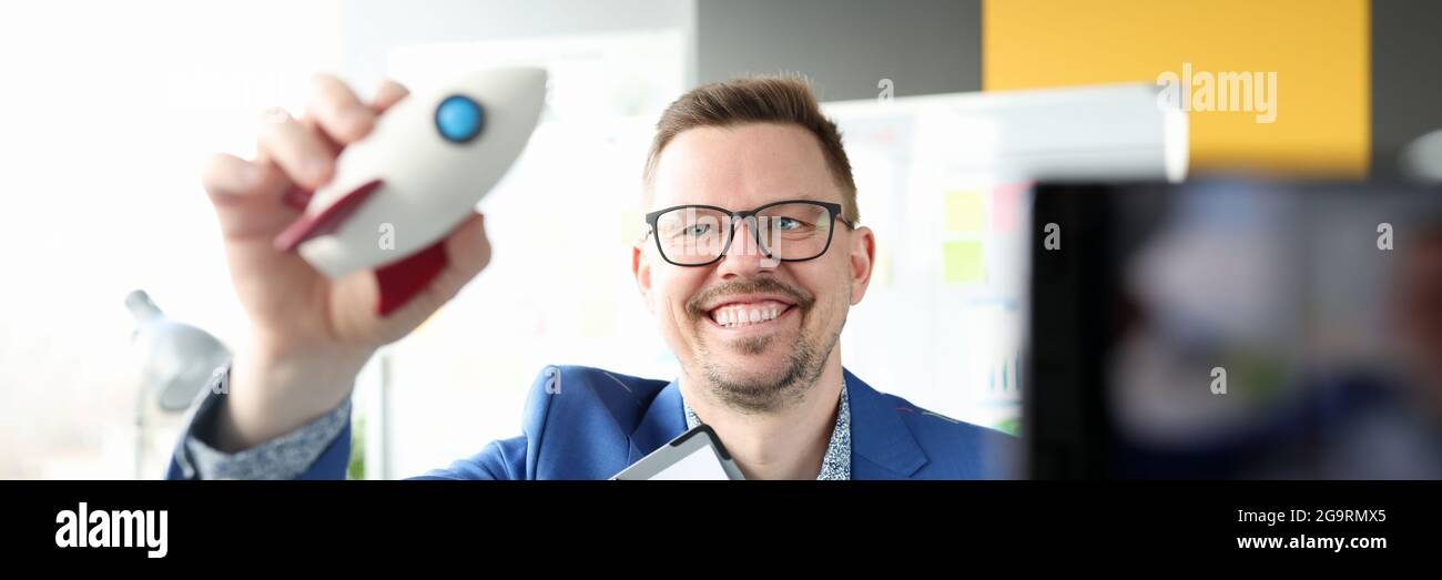 Uomo sorridente che tiene in mano il razzo e le carte aziendali Foto Stock