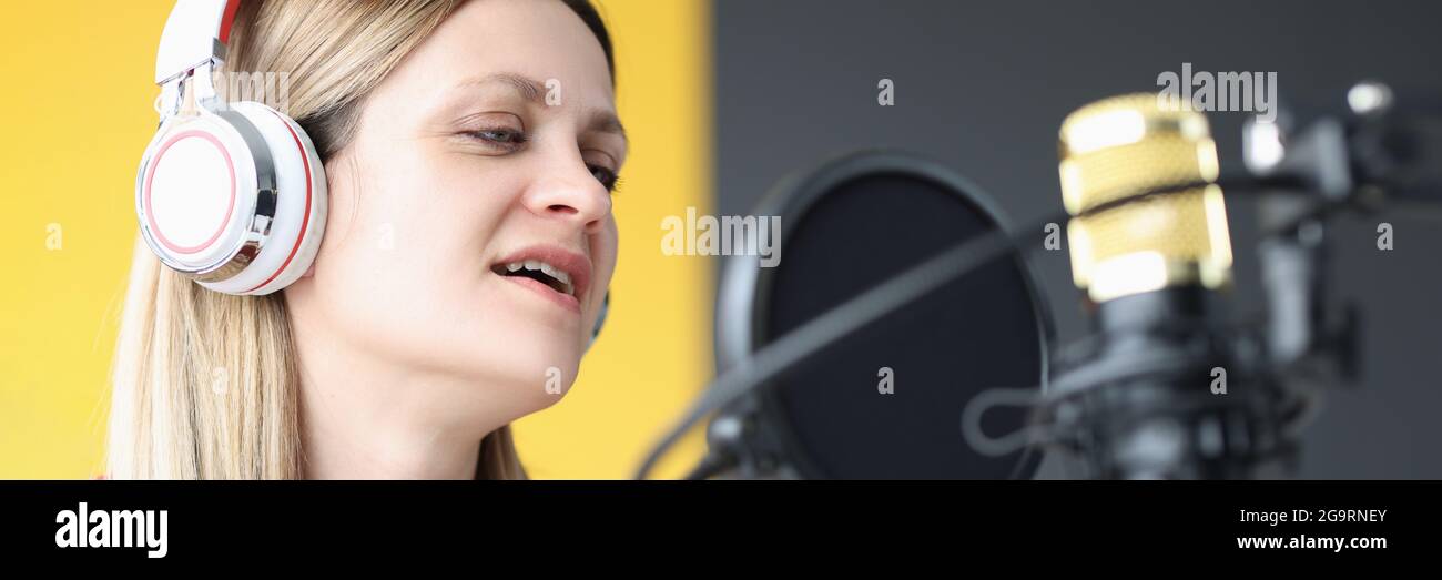 Ritratto della donna che canta nelle cuffie davanti al microfono Foto Stock