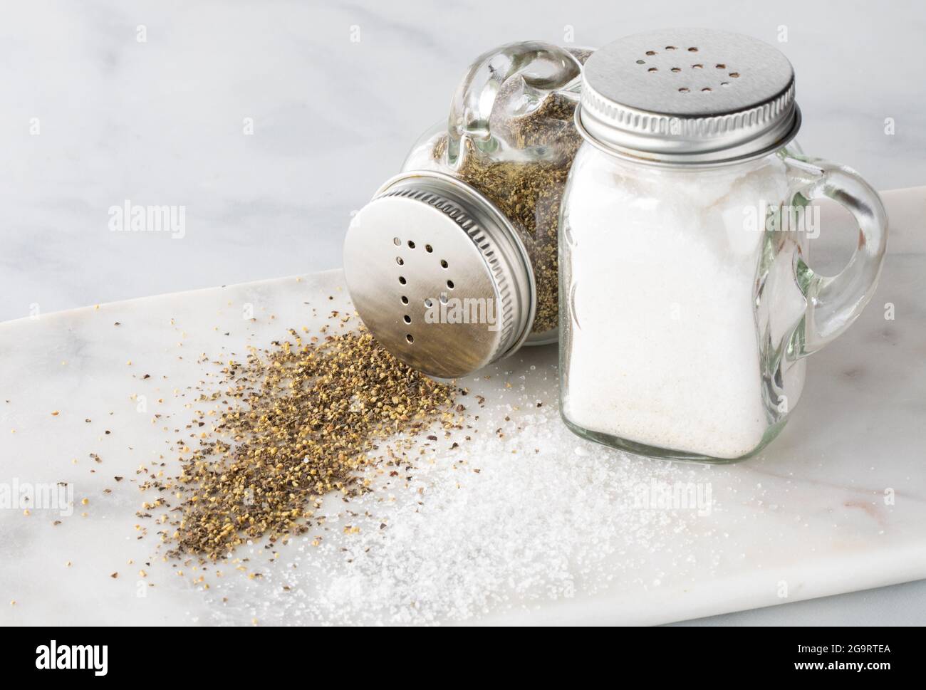Primo piano di shaker per sale e pepe con sale e pepe rovesciati davanti e il pepe rovesciato. Foto Stock