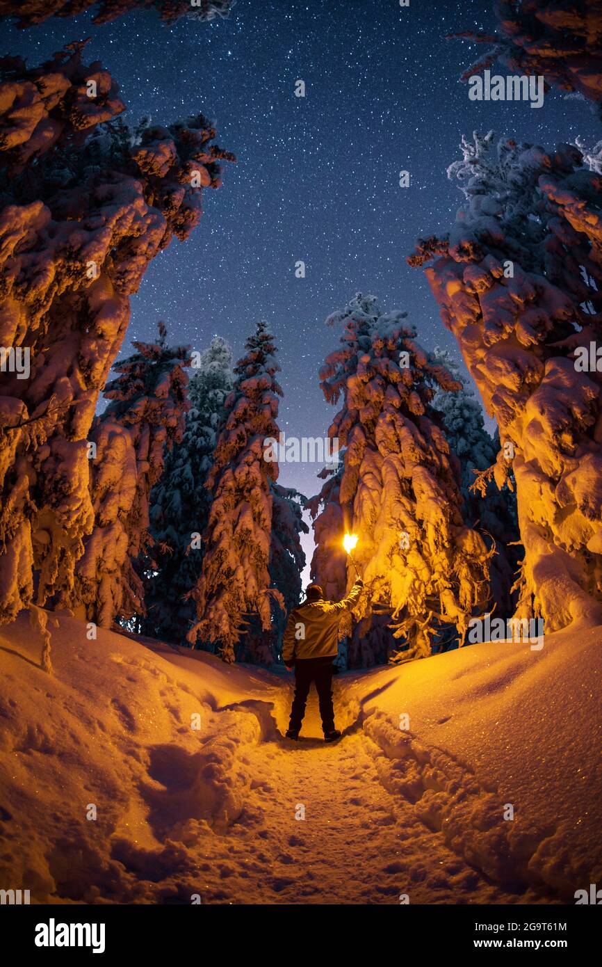 Uomo con una torcia in montagna di notte nella neve Foto Stock
