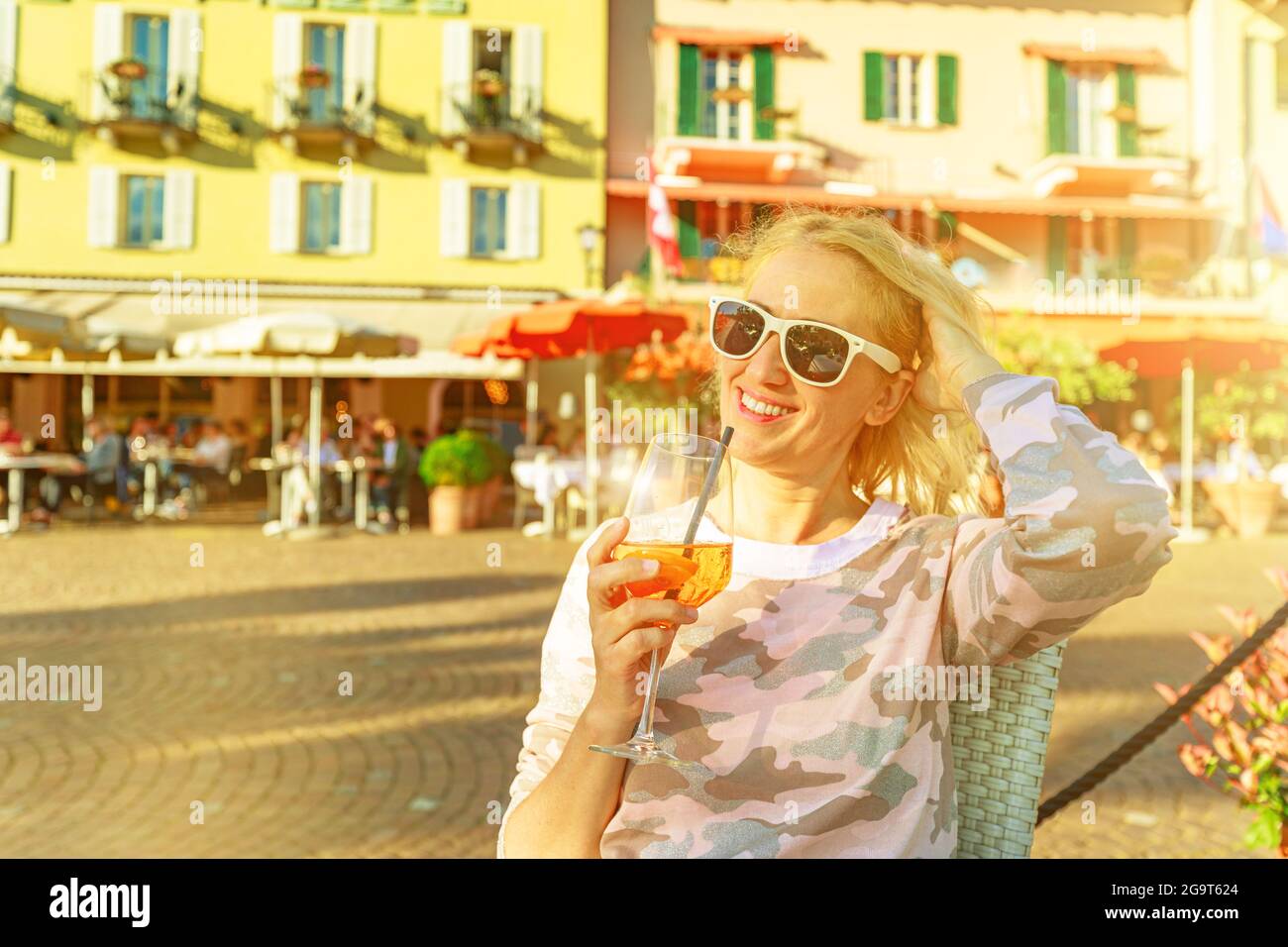 Il turista beve un cocktail sul lungolago in un pub di strada della città di Ascona in Svizzera, nel Canton Ticino sul Lago Langensee al tramonto. Foto Stock