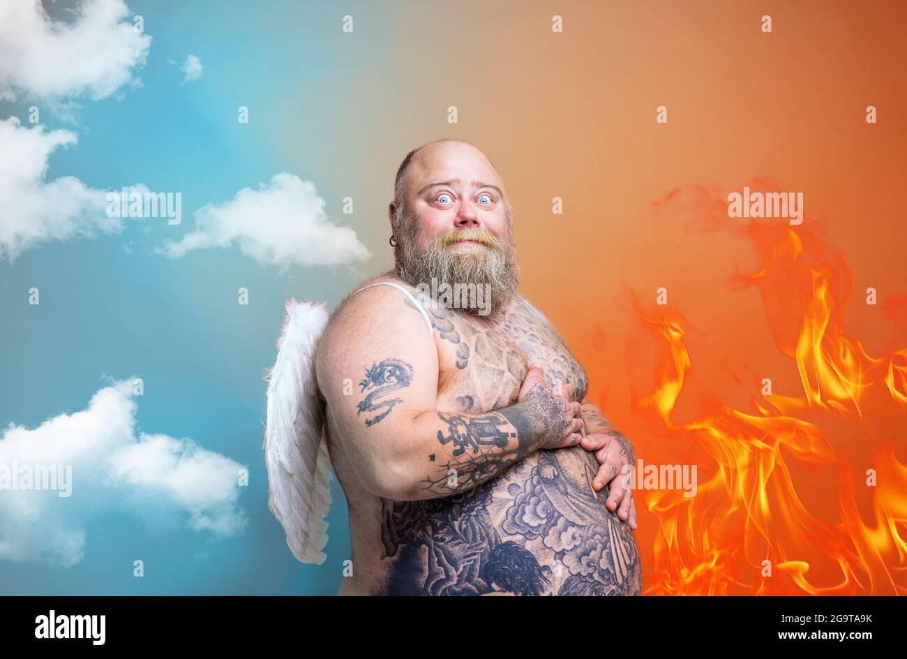 Uomo grasso stupito con barba, tatuaggi e ali agisce come un angelo Foto Stock