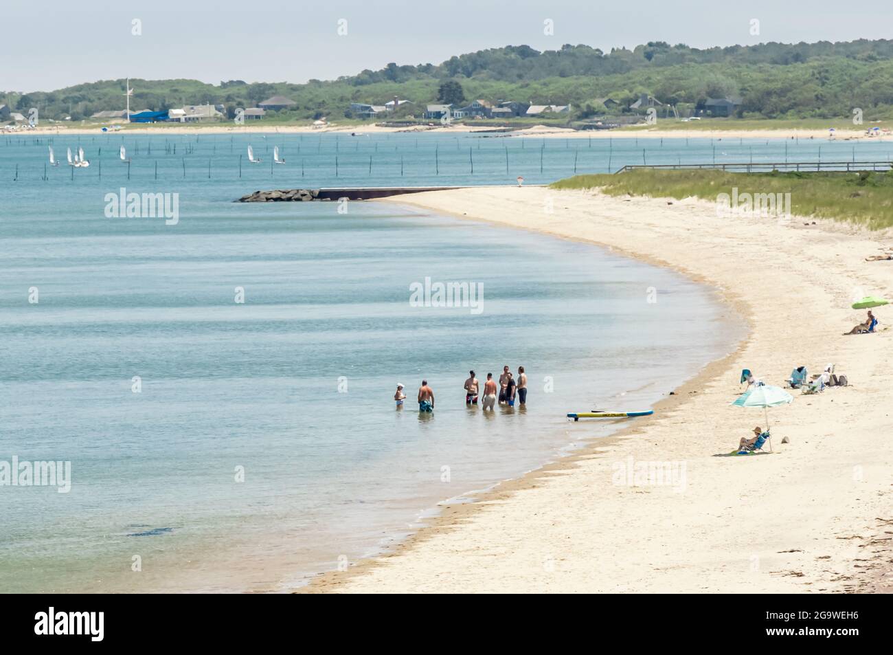Paesaggio della spiaggia con persone in piedi in acqua e la gente sulla spiaggia, Amagansett, NY Foto Stock
