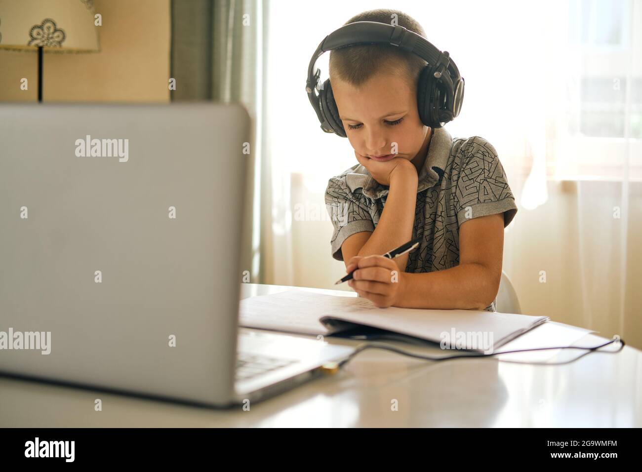 Scolaresche in cuffia utilizzando un computer portatile mentre si lavora a casa o durante la lezione online. Concetto di formazione online. Foto Stock