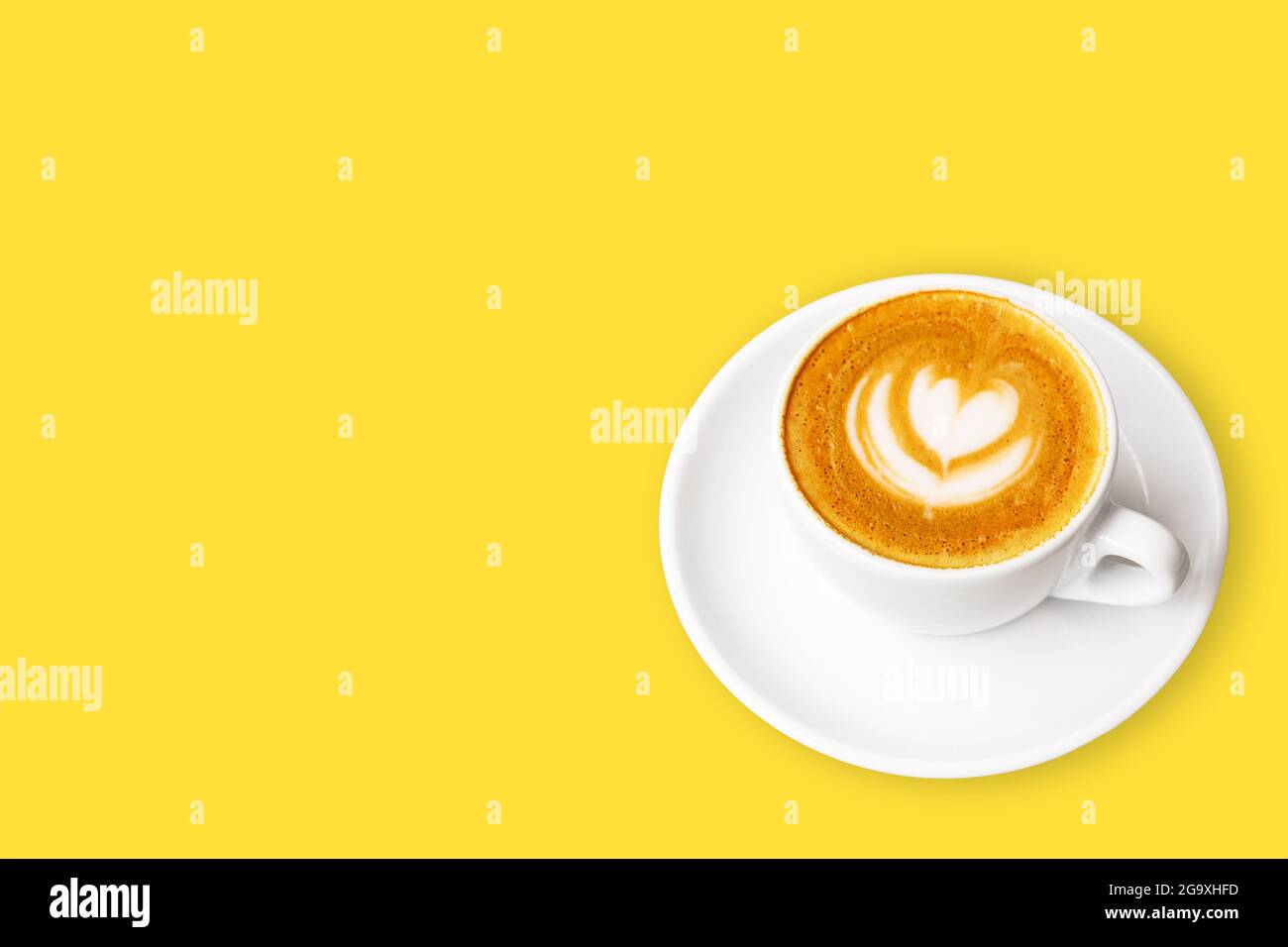 Tazza bianca di cappuccino con latte art su sfondo giallo. Foto Stock