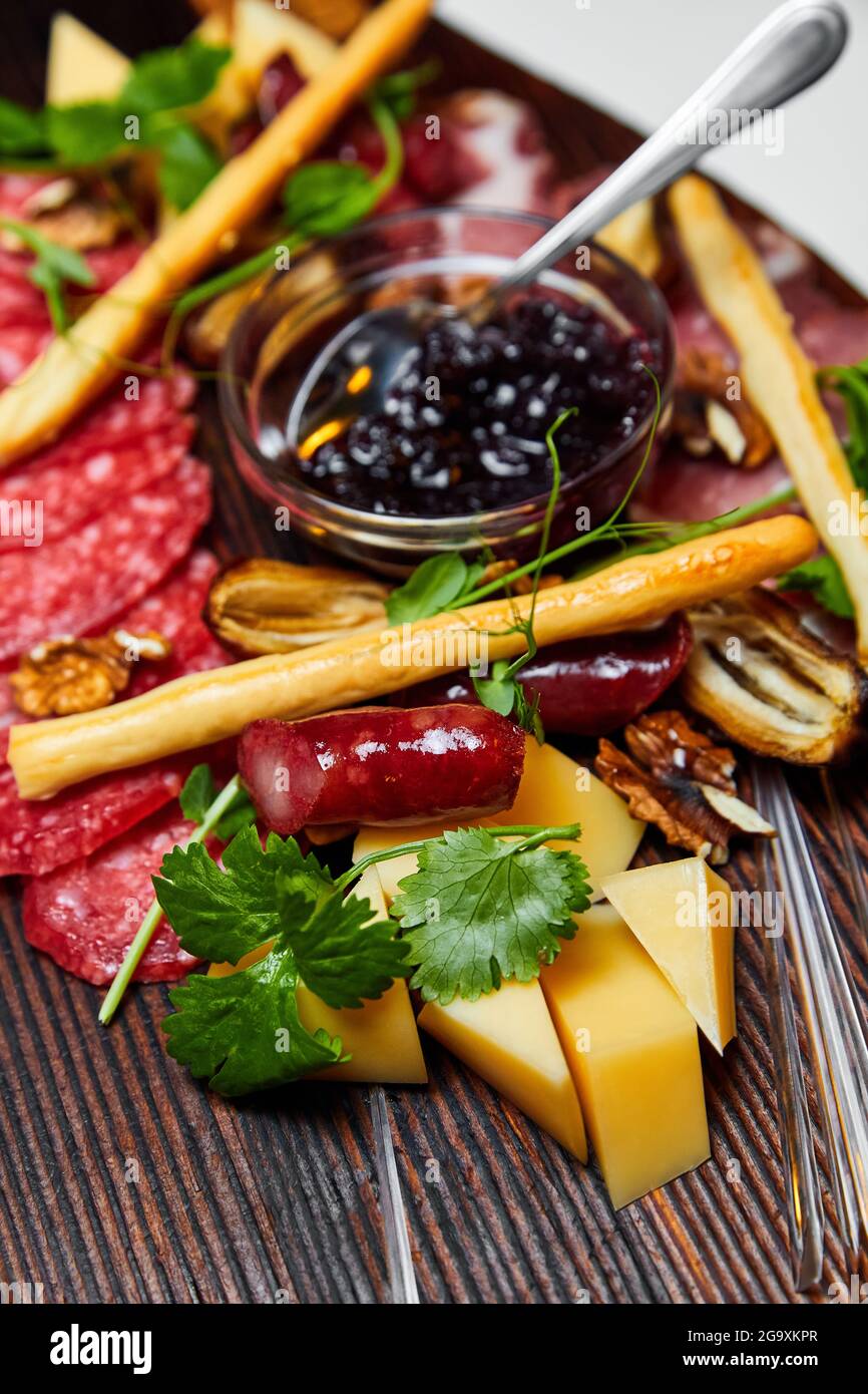 Formaggi assortiti e prelibatezze di carne su tavola di legno. Primo piano, messa a fuoco selettiva Foto Stock