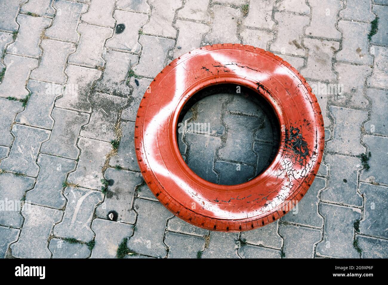 Vecchio pneumatico di automobile verniciato in rosso per gli scopi decorativi sulla strada. Foto Stock