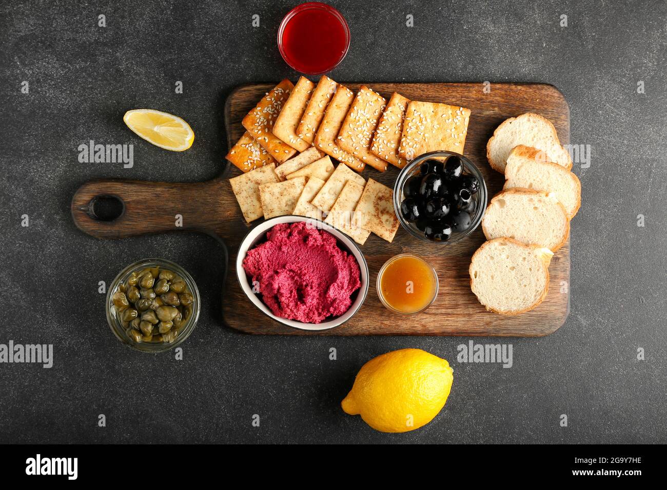 Composizione con gustoso hummus di barbabietola, spuntini e salse su fondo scuro Foto Stock