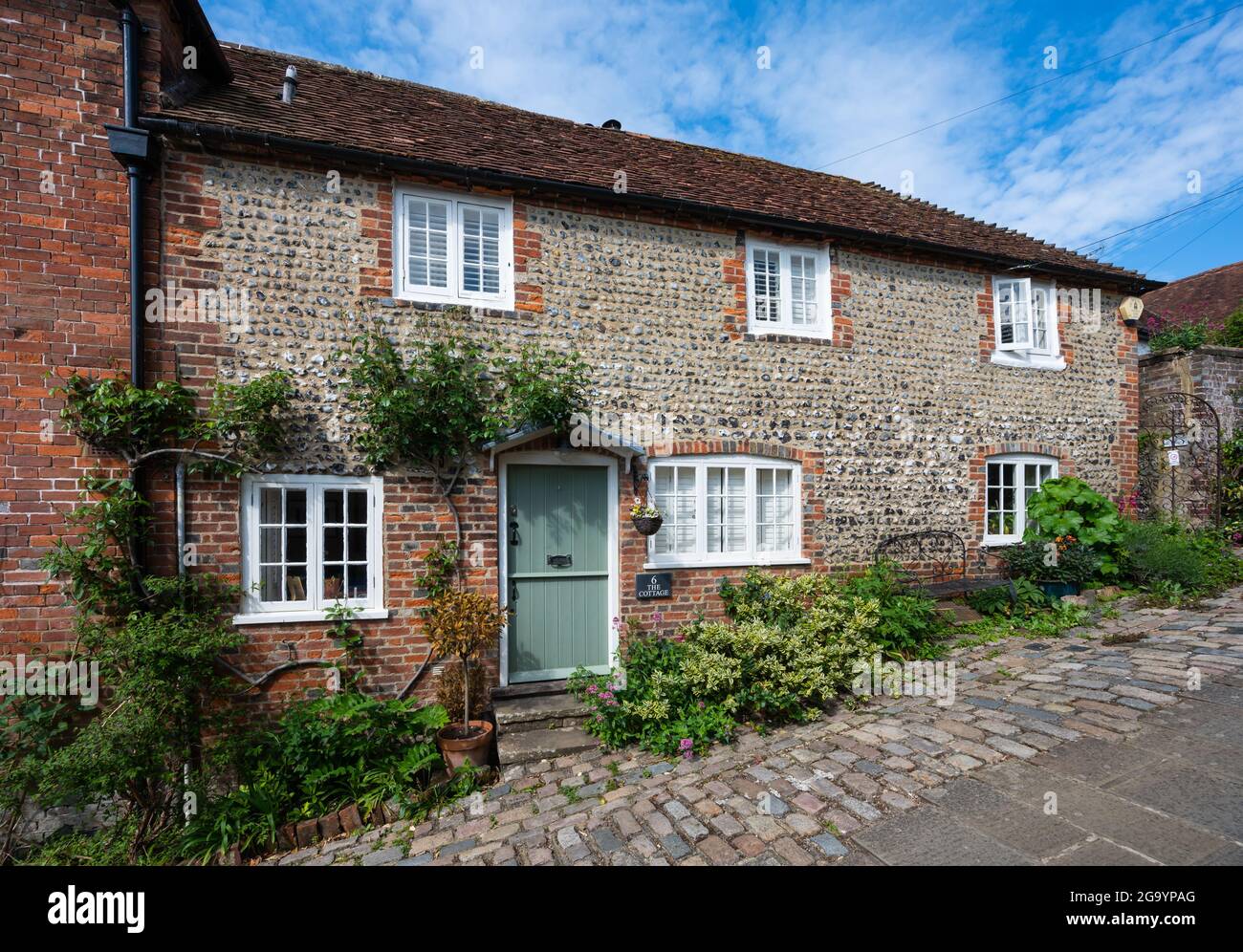 A Grade II elencato inizio 19 ° secolo (1800) cottage a 2 piani con pietra focaia e pareti di mattoni rossi su una collina su Bakers Arms Hill, Arundel, West Sussex, Regno Unito. Foto Stock
