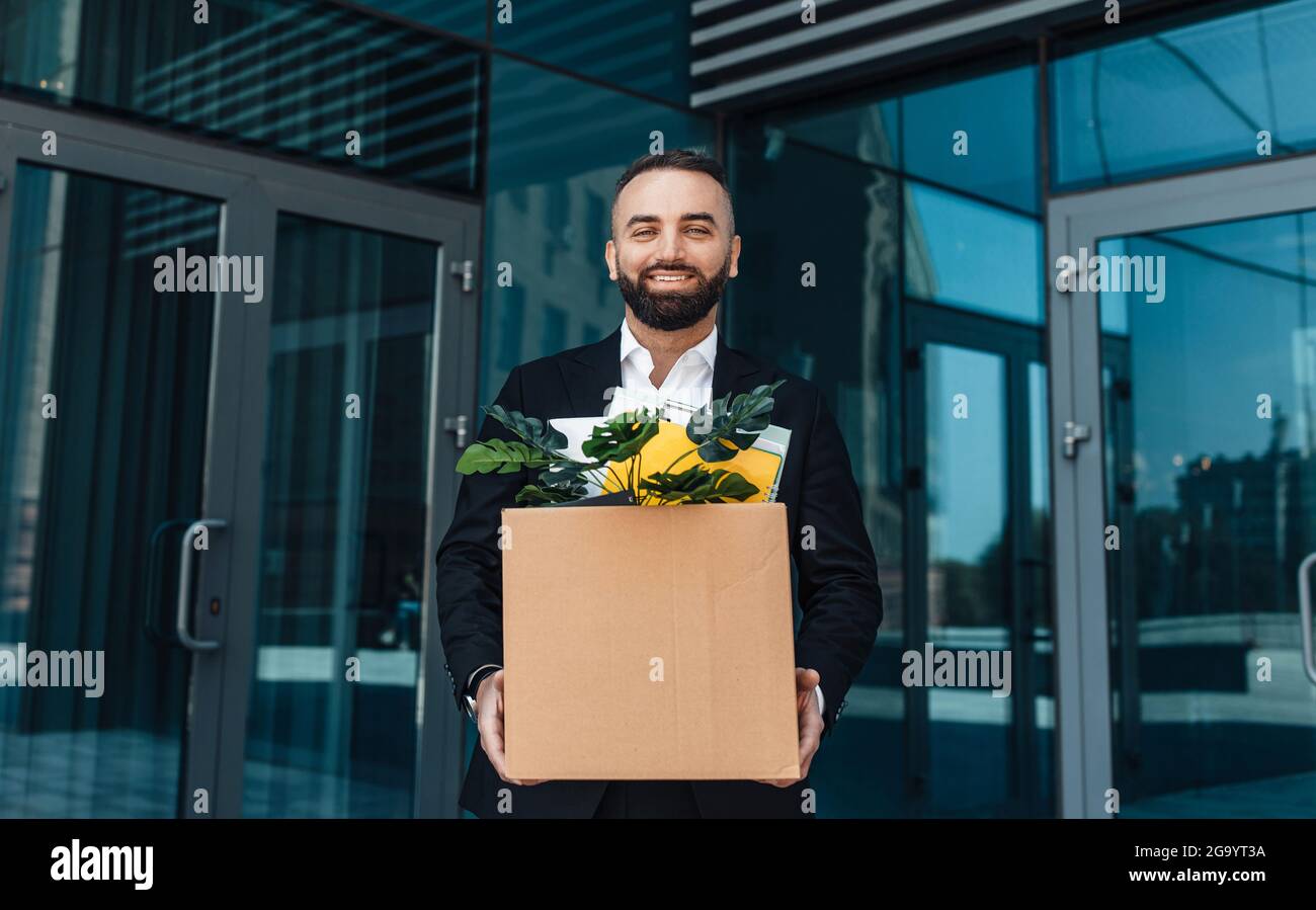 Dopo la quarantena e il blocco. Uomo d'affari felice con scatola degli effetti personali torna al lavoro d'ufficio Foto Stock