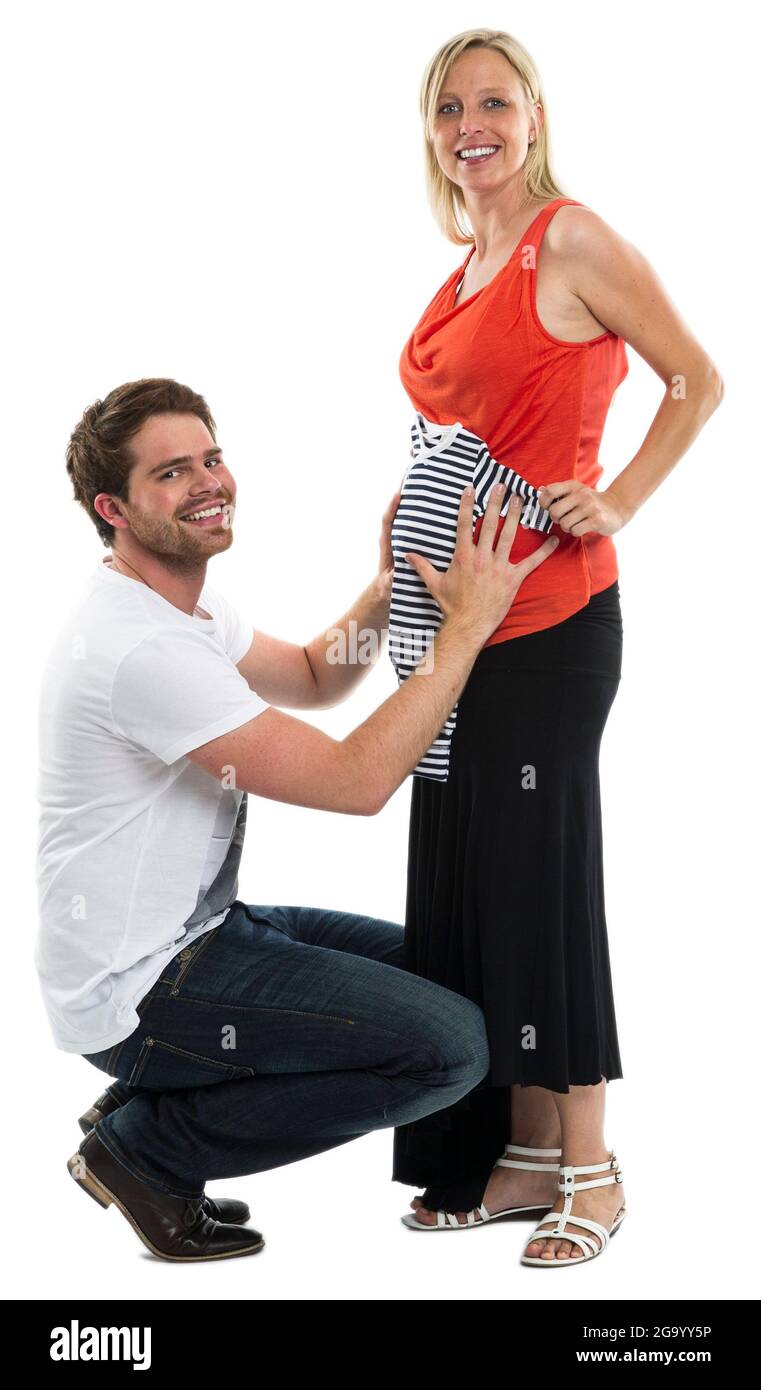 Il padre in attesa tiene felicemente un vestito romper davanti al bump del bambino della sua moglie incinta, Germania Foto Stock