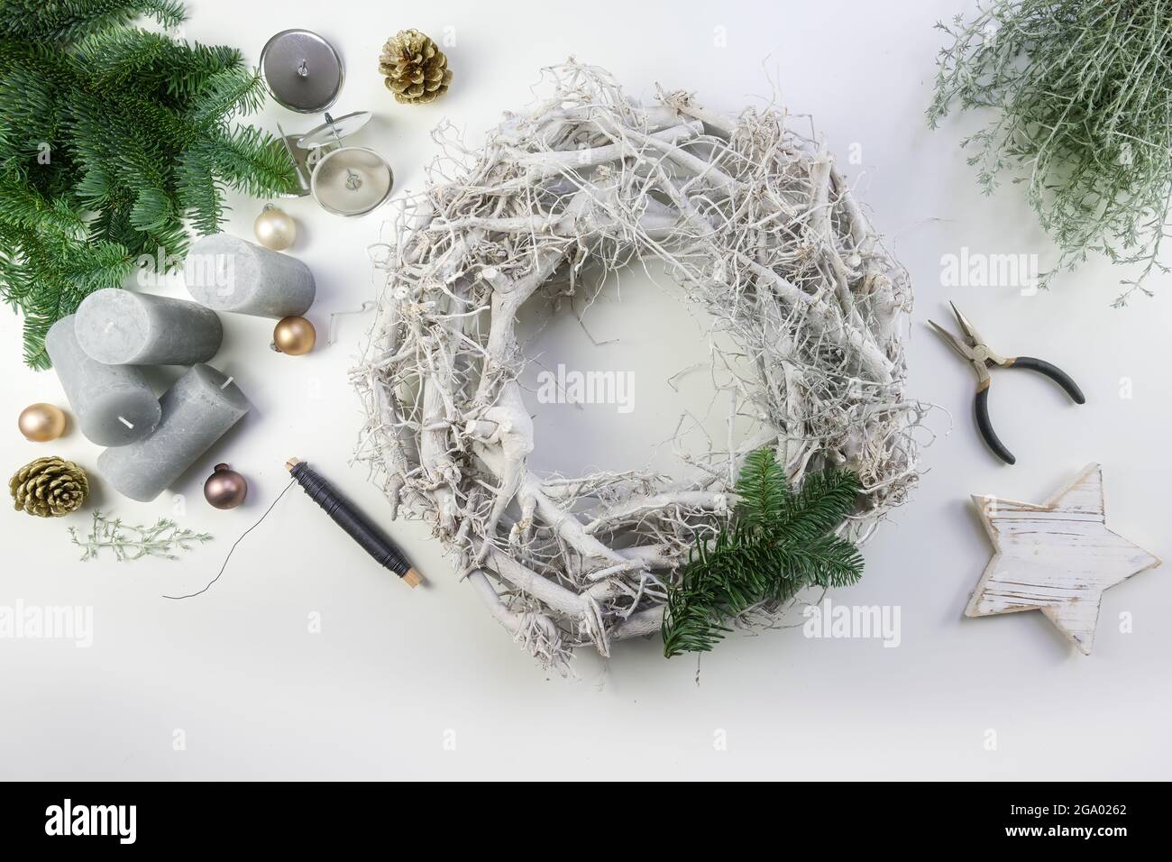 Decorazione di una corona di avvento da legno bianco con rami di fuoco verde, palline di Natale dorate pallido e candele grigie per una disposizione invernale naturale, h Foto Stock