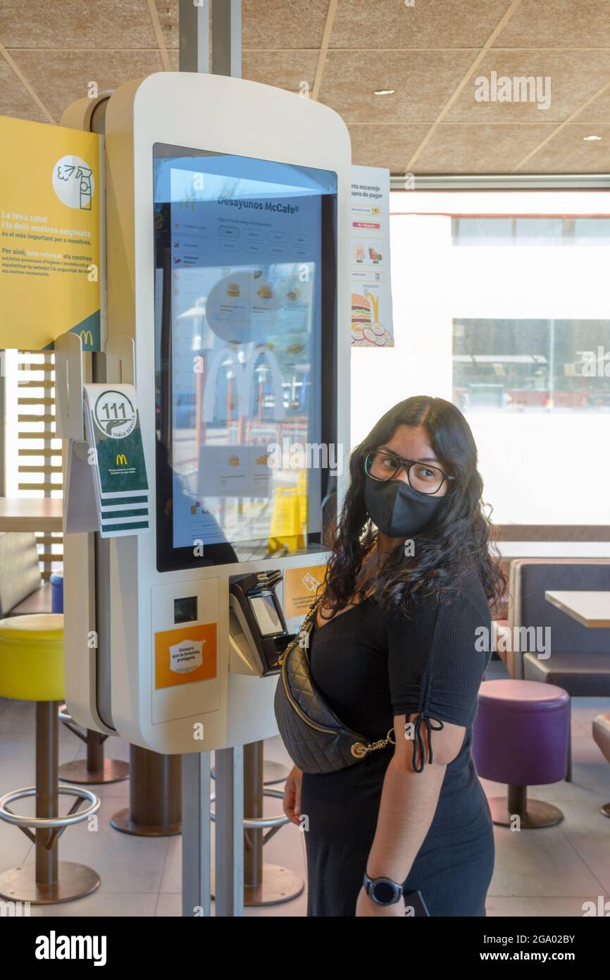 Mallorca, Spagna, 07-27-2021: Giovane donna che effettua un ordine su un touch screen con una maschera nel ristorante fast food di Macdonald nell'era post-pandemica, Foto Stock