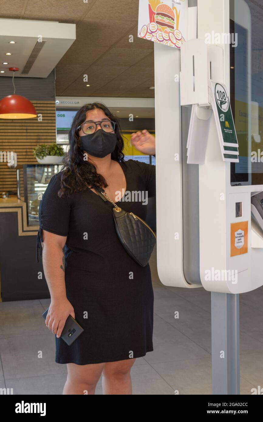 mallorca, spagna, 07-27-2021, giovane donna che effettua un ordine su un touch screen con una maschera in un ristorante fast food di Macdonald, nel post-pandemic er Foto Stock
