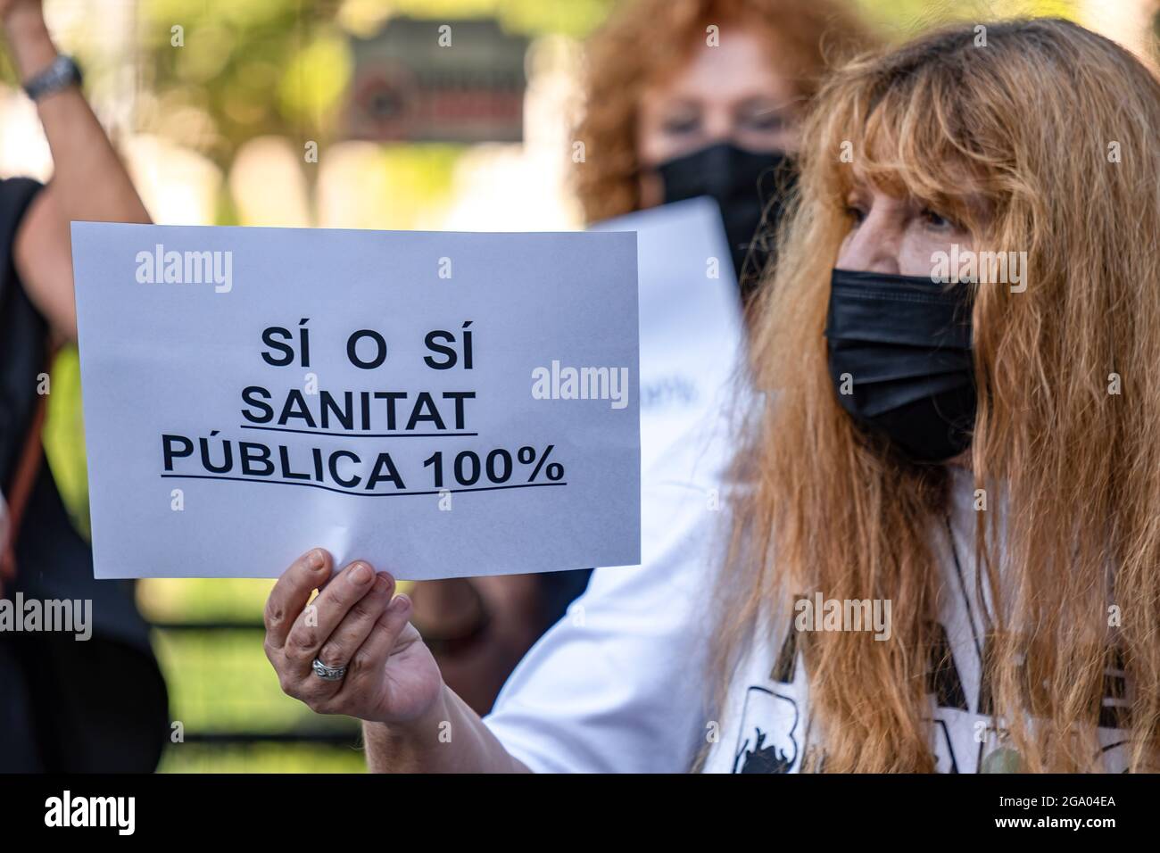 Barcellona, Spagna. 28 luglio 2021. Durante la dimostrazione, un manifestante visualizza un cartello che chiede il 100% di salute pubblica. L'entità sociale Marea Blanca de Catalunya ha dimostrato contro la risoluzione del Servizio sanitario Catalano che sospende l'assistenza sanitaria primaria non urgente per tre mesi a causa del traboccamento prodotto dalla saturazione del sistema sanitario da parte dei pazienti di Covid19. Credit: SOPA Images Limited/Alamy Live News Foto Stock