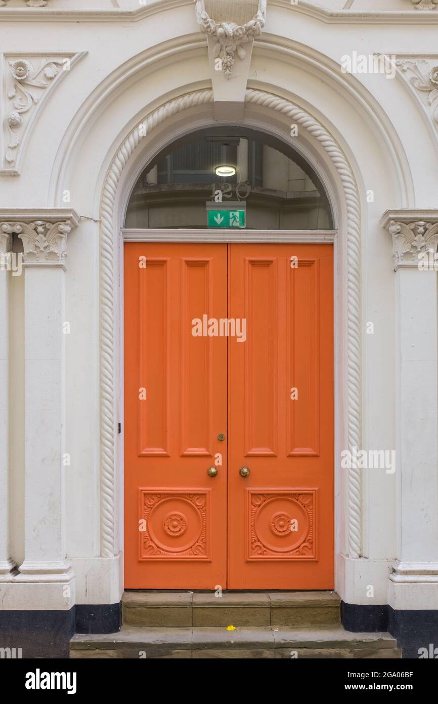 Vecchie porte doppie in legno dipinte di arancione all'entrata di un edificio in Colmore Row, Birmingham, Regno Unito Foto Stock