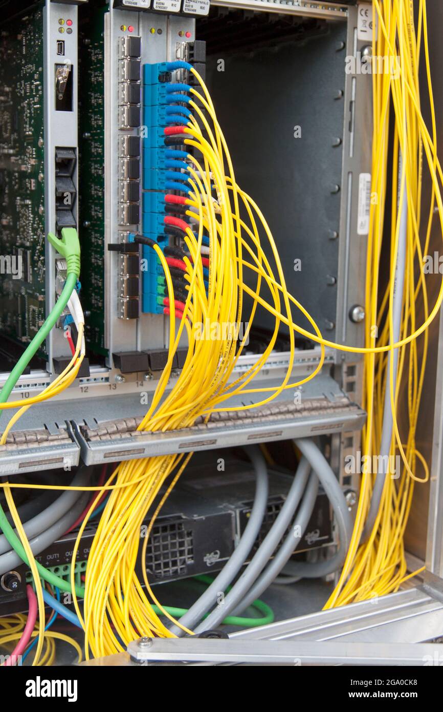 Einblick in einen Verteilerkasten mit zahlreichen verkabelten Glasfaserkabeln eines Netzwerks beim Breitbandsausbau des Gigabit-schnellen Internets Foto Stock