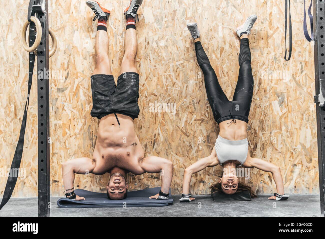 donna e uomo che fanno il cavalletto sulla parete della palestra, crossfit Foto Stock