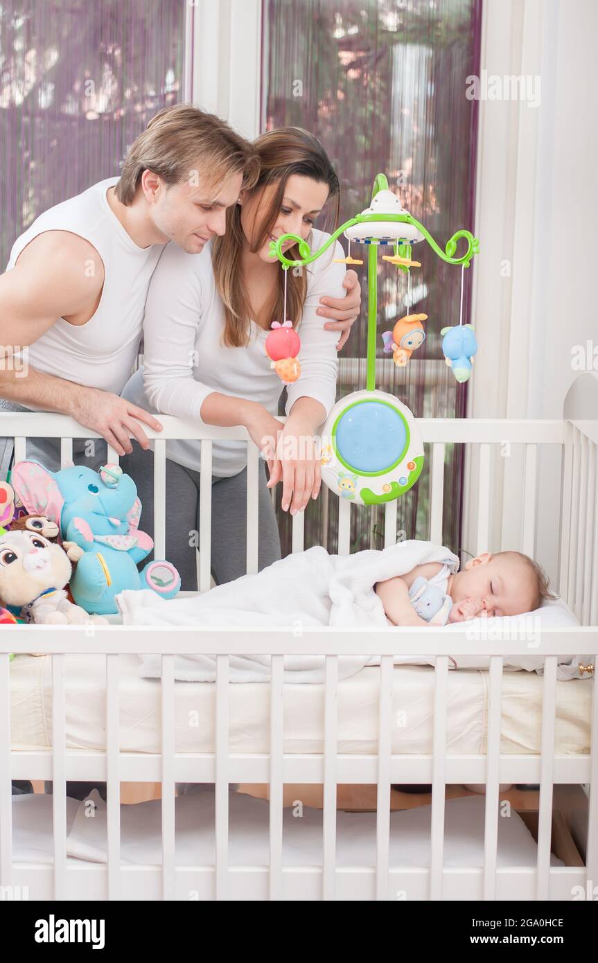 Felici genitori in piedi accanto al letto del bambino. Felicità e orgoglio. Foto Stock