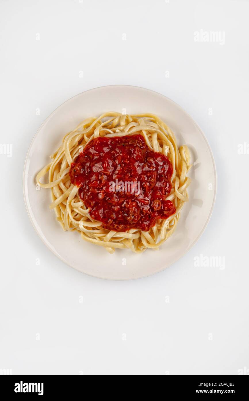 Spaghetti e salsa su un piatto su uno sfondo di studio isolato Foto Stock