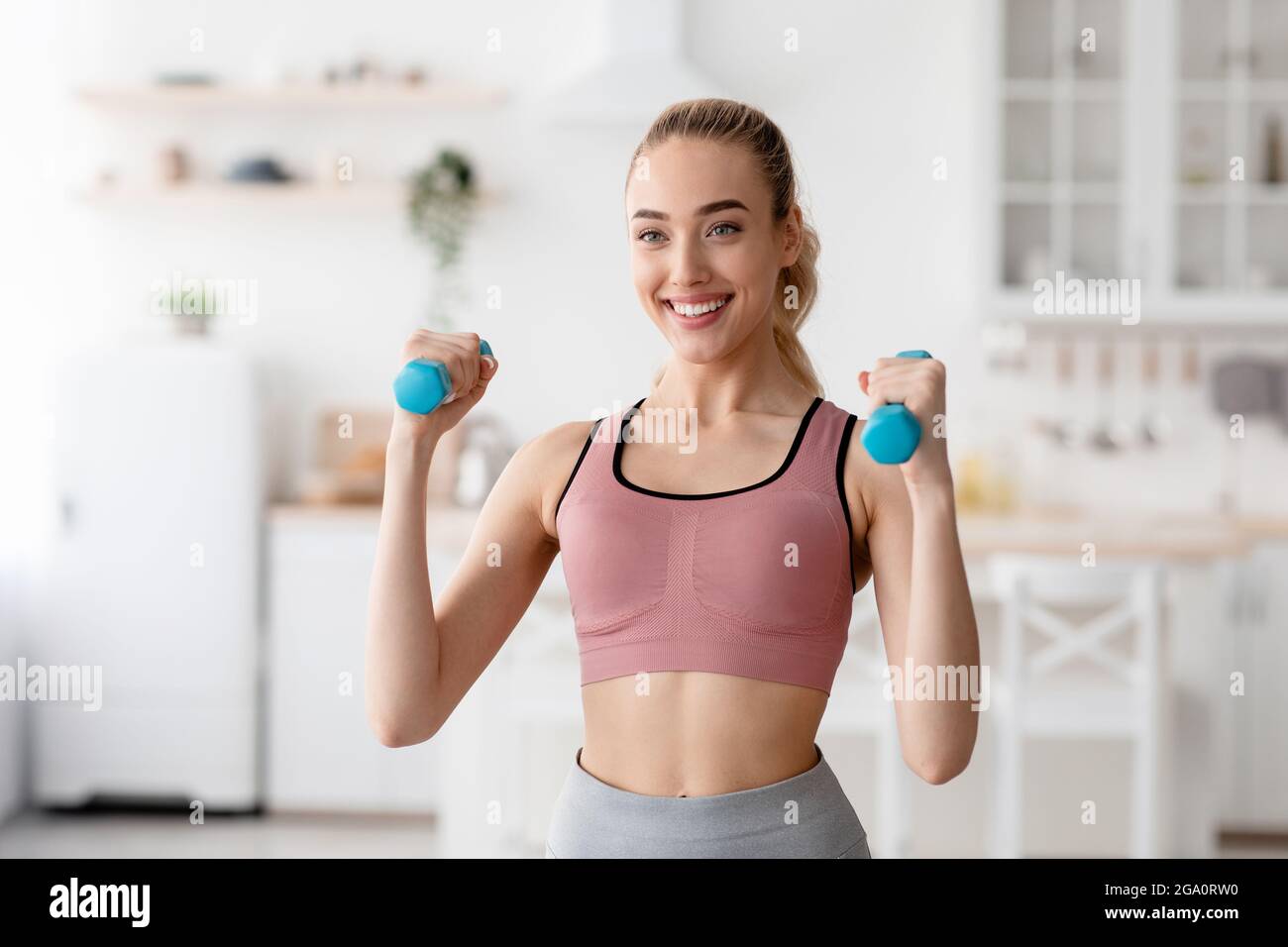 L'atleta felice lavora a casa, si esercita per le mani e si tiene in forma durante il blocco COVID-19 Foto Stock