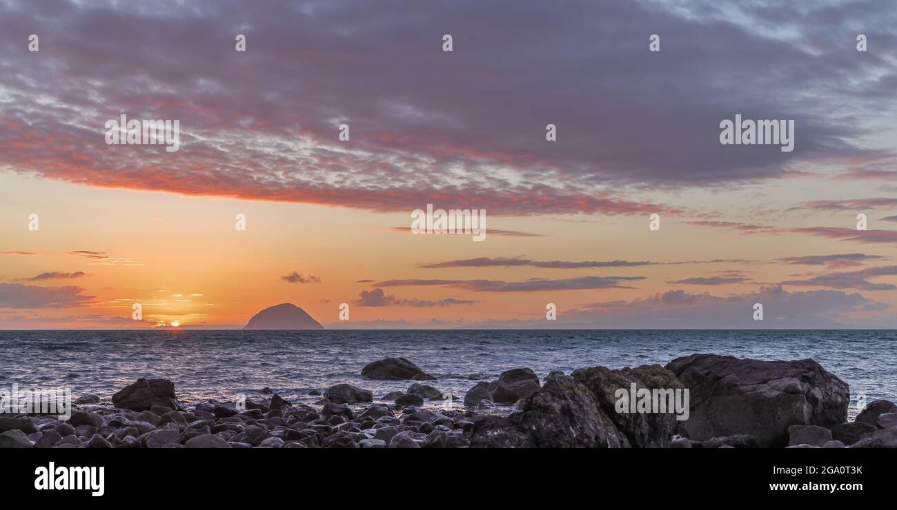 Tramonto sul Mare d'Irlanda e Ailsa Craig preso da Lendalfoot, Sud Ayrshire, Scozia con rocce in primo piano Foto Stock