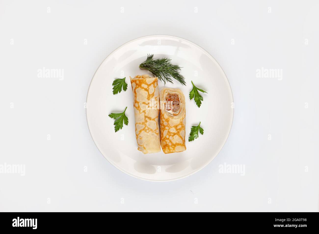 Pancake e verde su un piatto su uno sfondo isolato Foto Stock