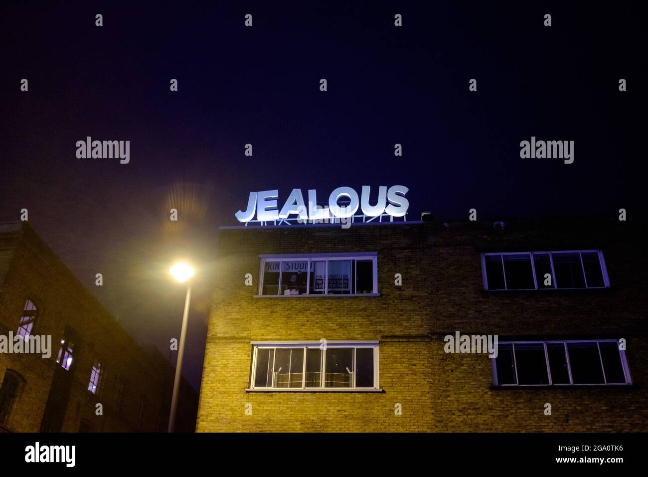 Scritta gelosa in un negozio di testo in cima a un edificio di Londra a tarda notte Foto Stock