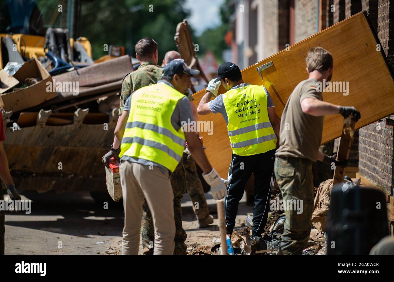 Erftstadt Blessem, Germania. 28 luglio 2021. I soldati e gli assistenti della Bundeswehr rimuovono i rifiuti ingombranti per la rimozione in una pala dell'escavatore dopo il disastro dell'alluvione. Dopo la tempesta con gravi distruzioni, il lavoro di pulizia continua. Credit: Jonas Güttler/dpa/Alamy Live News Foto Stock