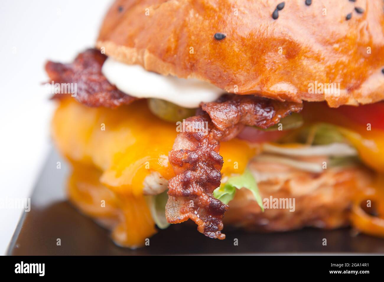 Cheeseburger con pancetta, insalata e patatine. Cibo ad alta caloria. Formaggio cheddar liscio fuso, prodotto in origine a Cheddar, nell'Inghilterra sud-occidentale. Foto Stock