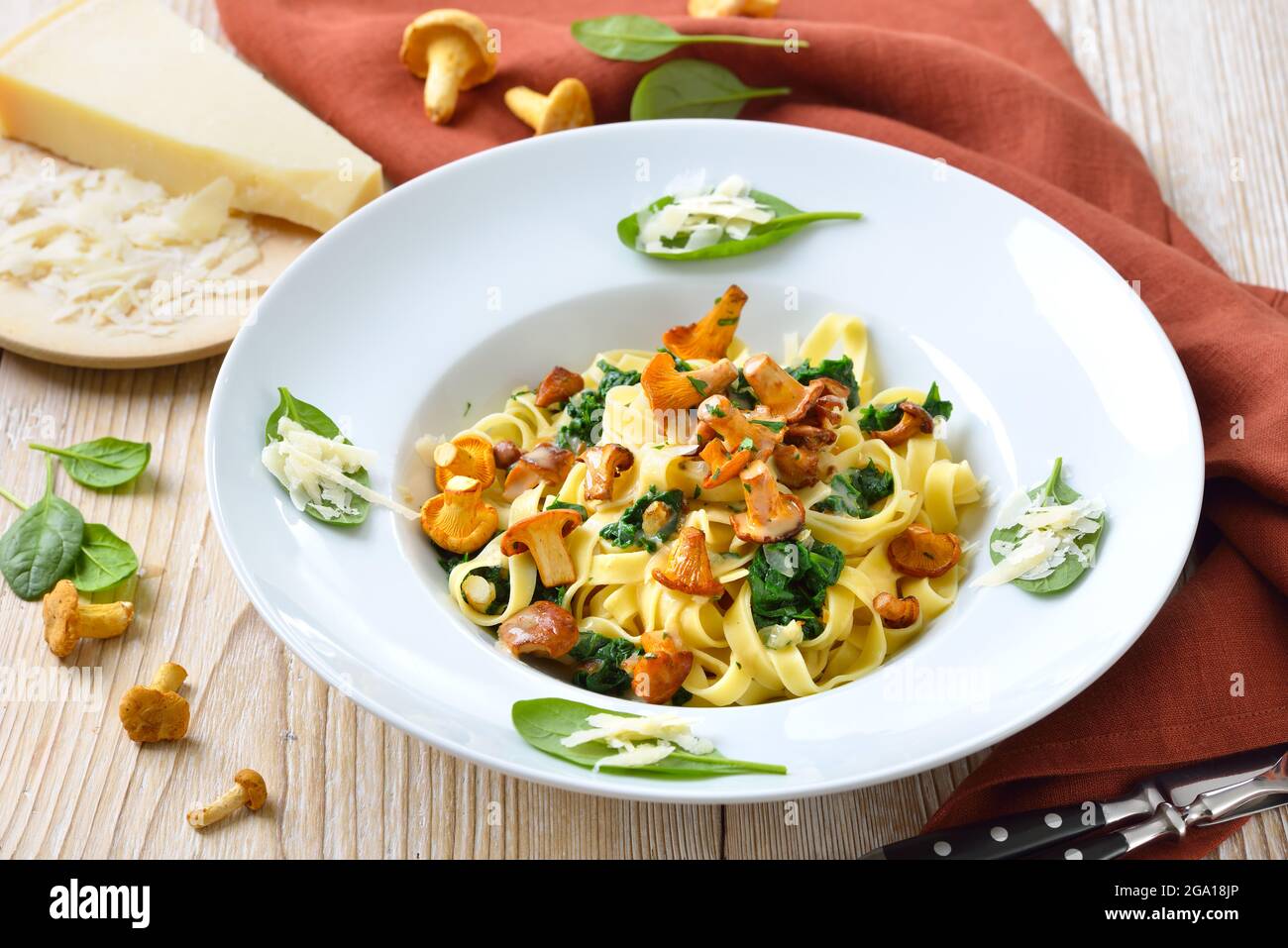 Deliziosa pasta italiana con chanterelle fresche, spinaci giovani, salsa alla crema e parmigiano Foto Stock