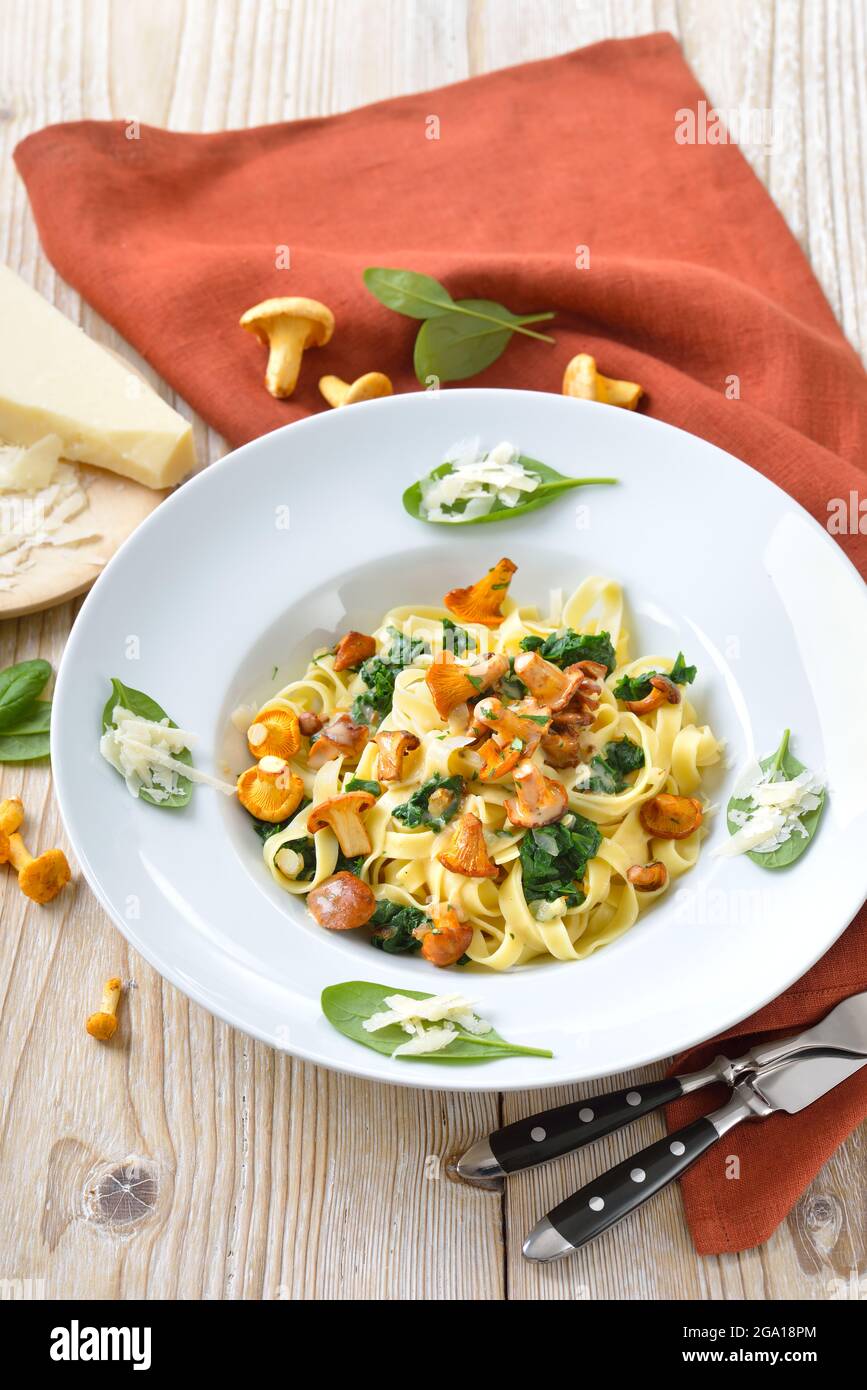 Deliziosa pasta italiana con chanterelle fresche, spinaci giovani, salsa alla crema e parmigiano Foto Stock