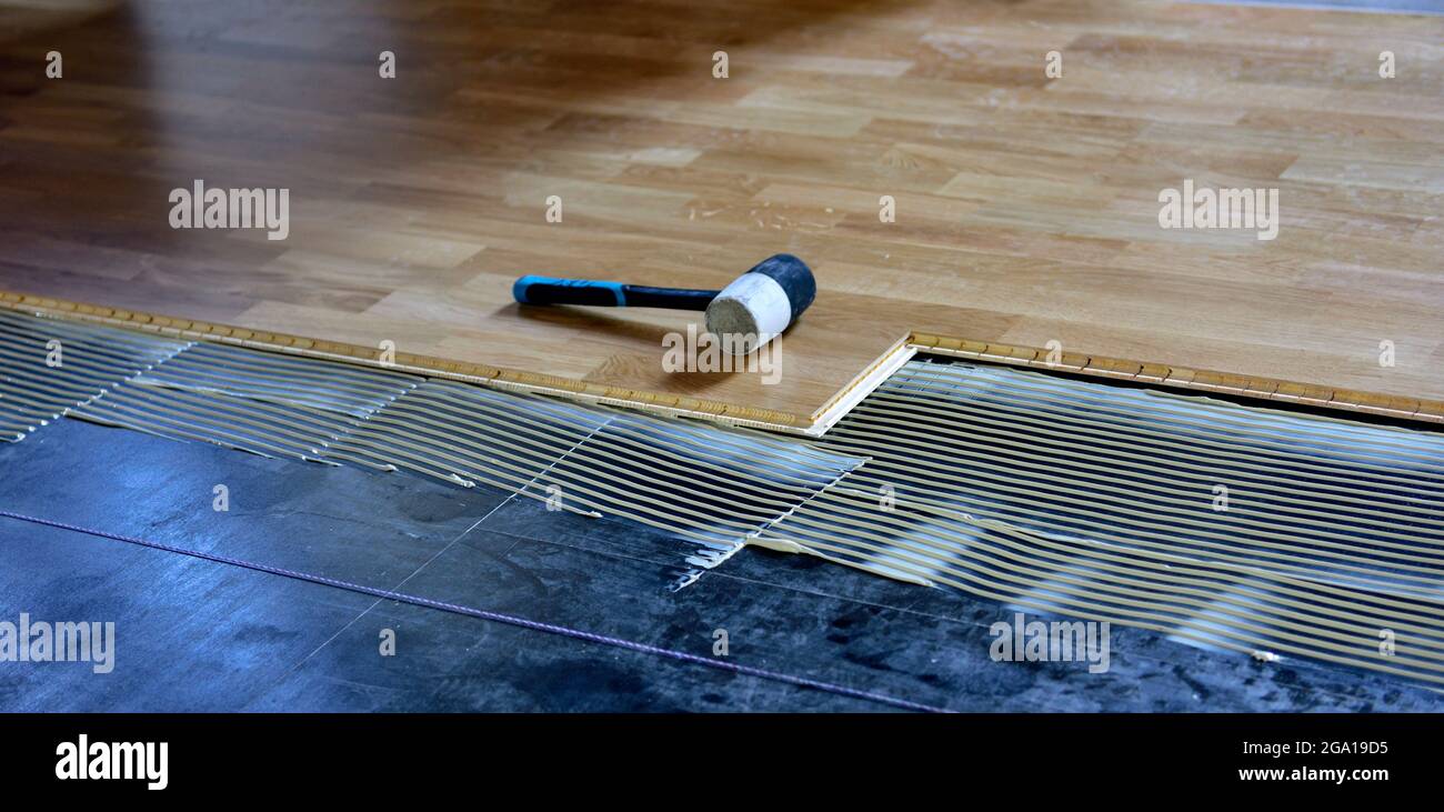 Installazione di pavimenti laminati con linguetta e scanalatura in legno con adesivo e mazzuolo in gomma Foto Stock