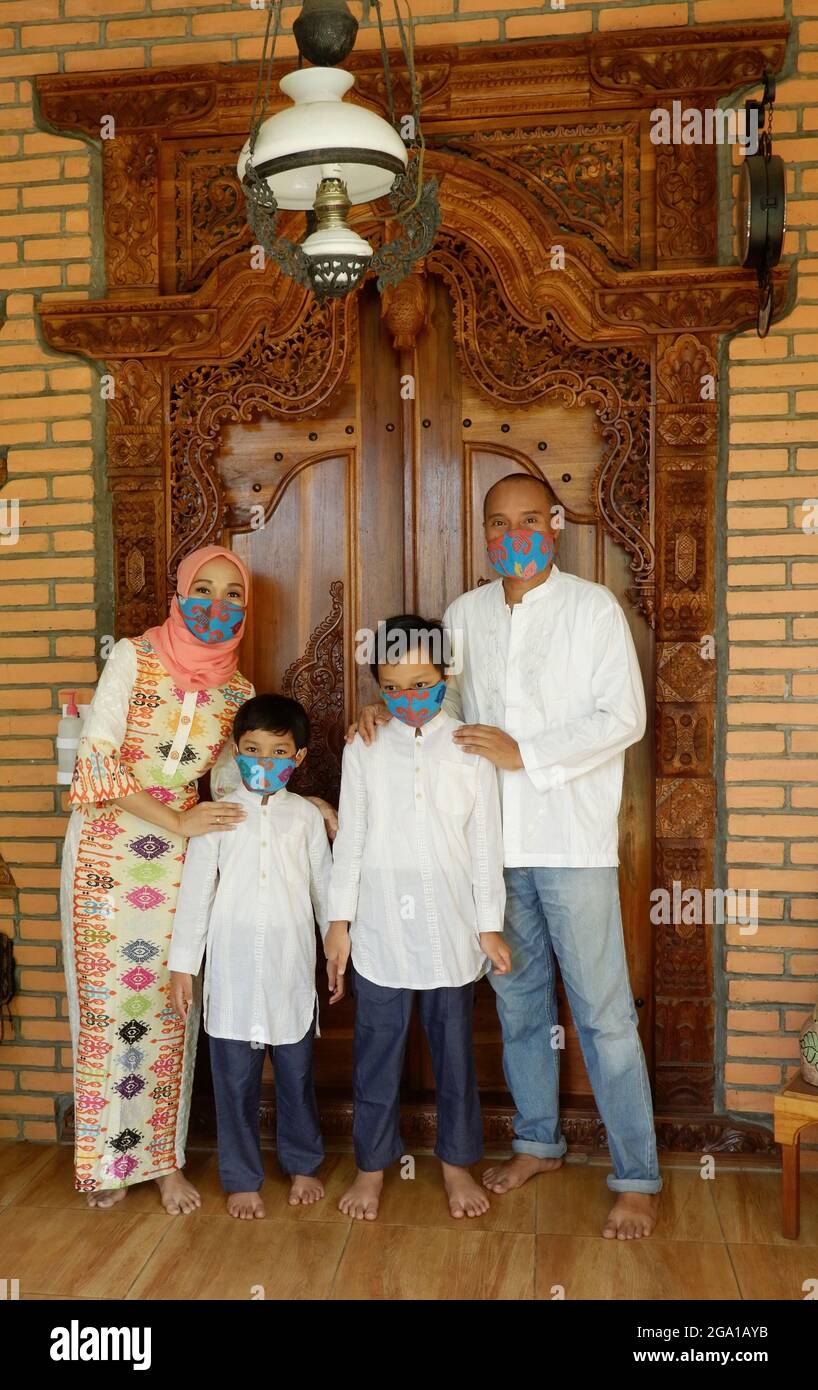 Una famiglia musulmana indossa il facemask e posa di fronte alla loro casa. Foto Stock