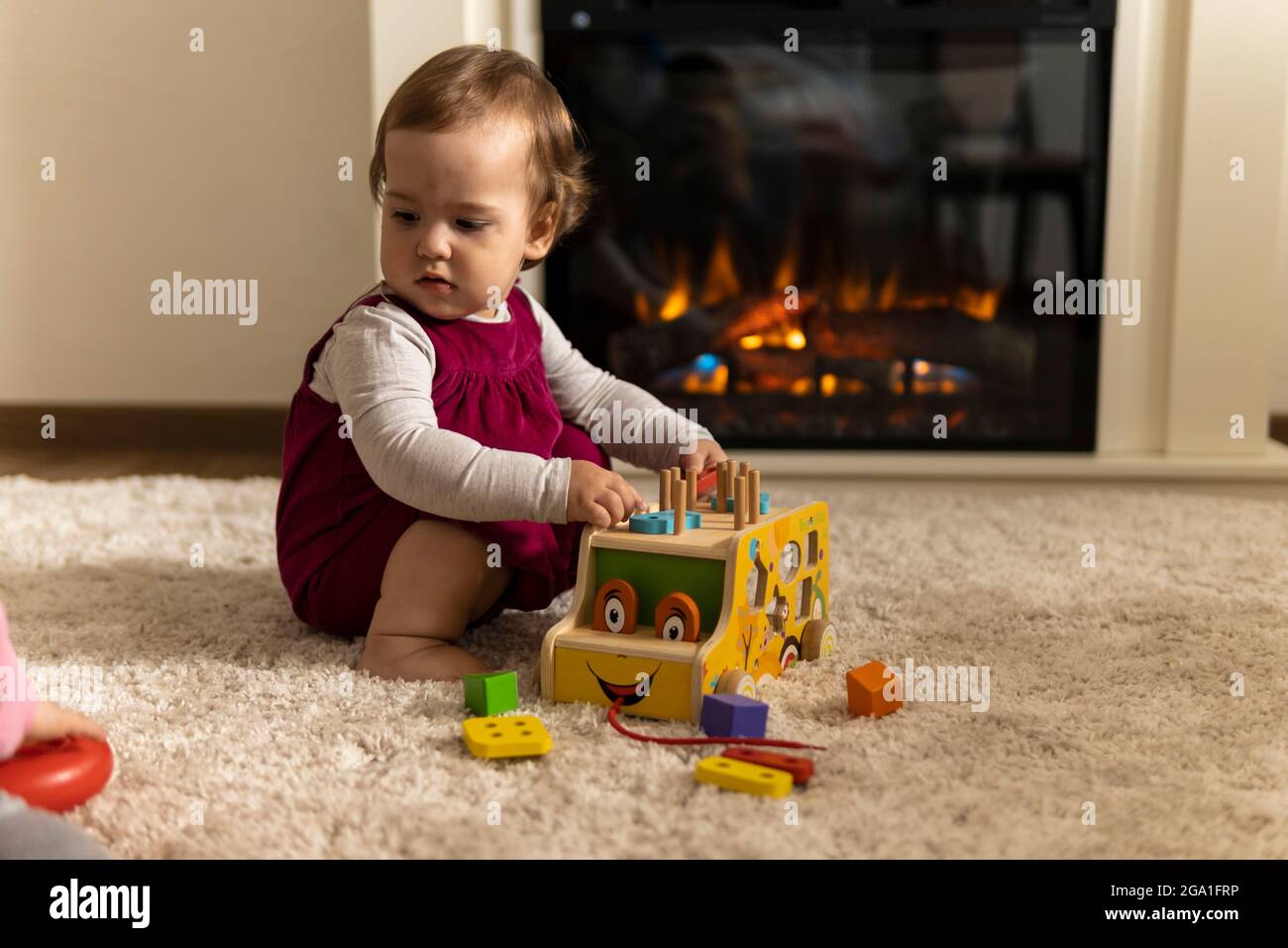 infanzia, sviluppo, abilità, giochi di motilità - piccolo bambino autentico bambina bambina compone specie forme colorate giocando legno giocattolo smistatore auto Foto Stock