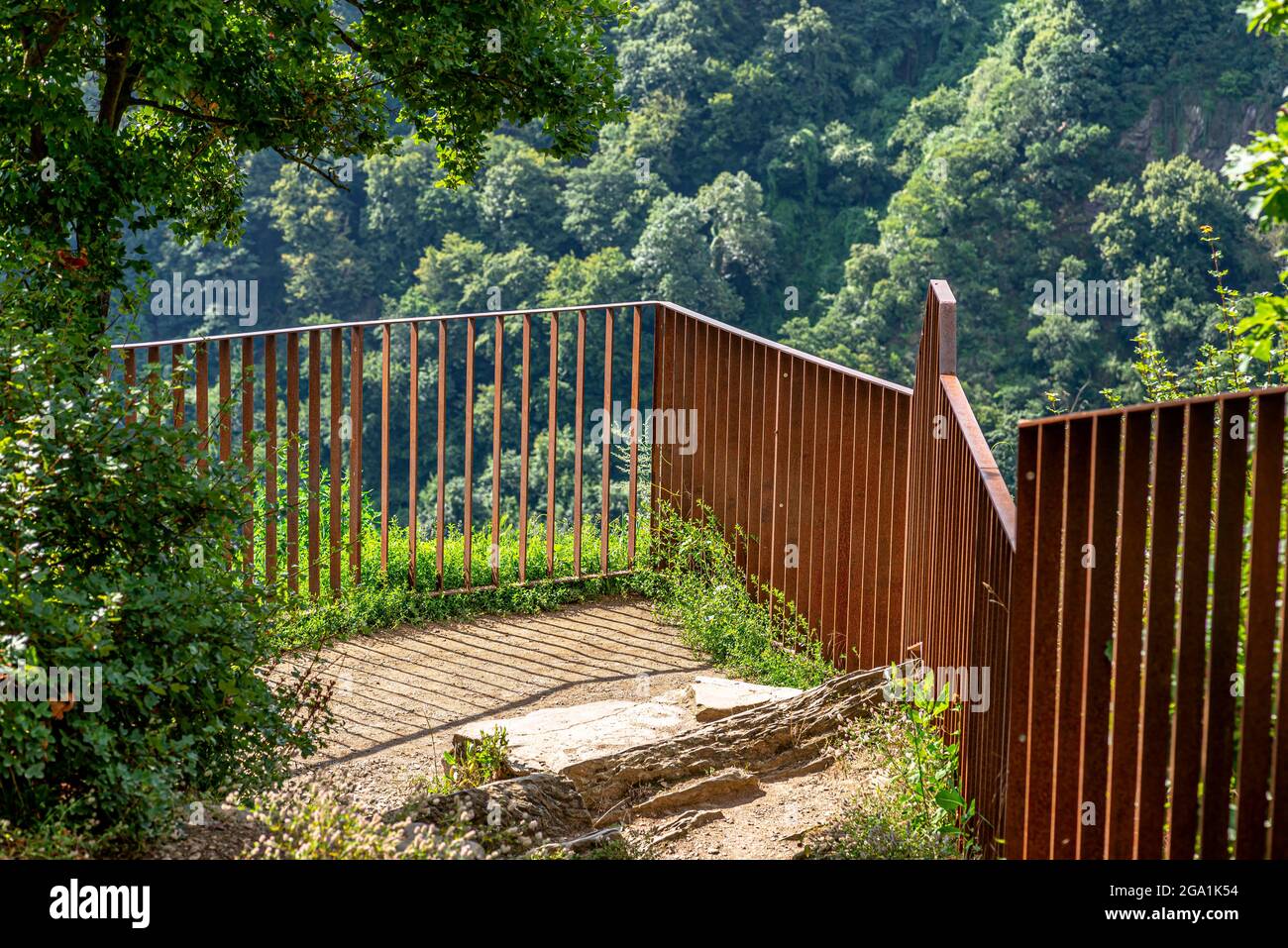Recinzione in metallo arrugginito ai margini della valle del fiume, alberi visibili sulle colline. Foto Stock