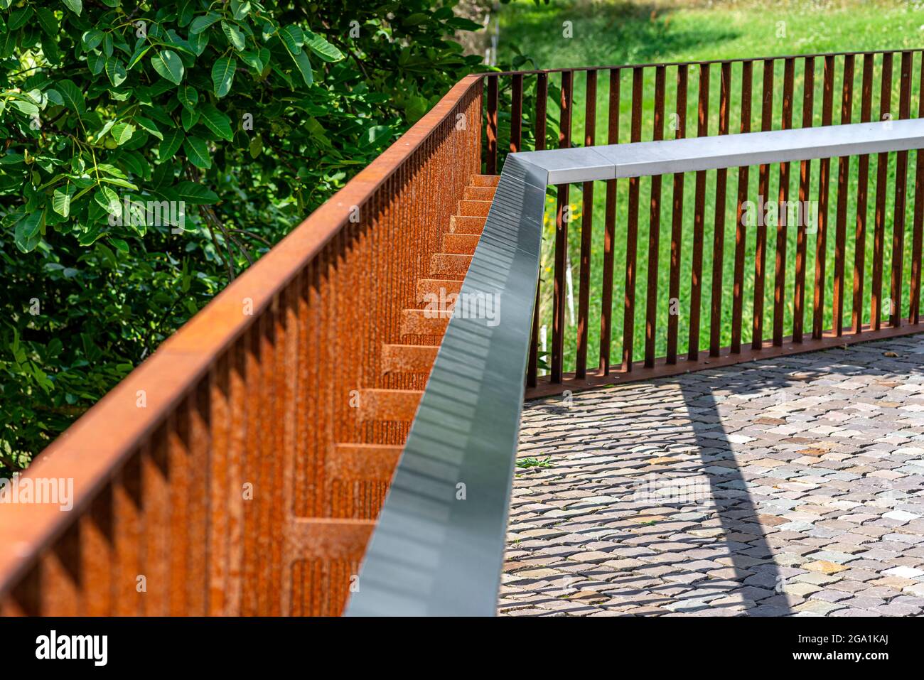 Recinzione in metallo arrugginito ai margini della valle del fiume, erba visibile. Foto Stock