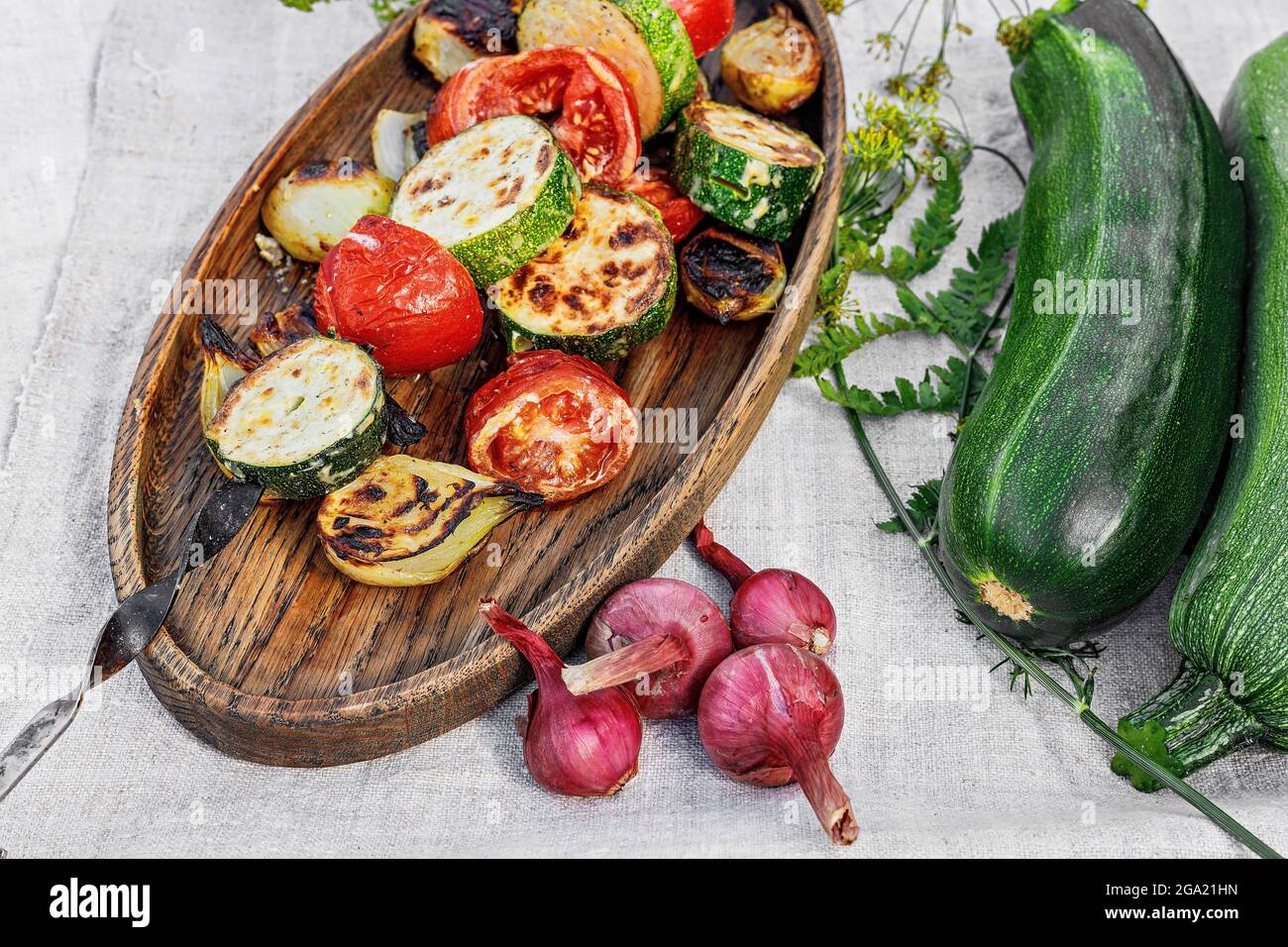 Kebab di verdure. Zucchine, pomodori e cipolle dolci su un piatto di legno. Verdure biologiche alla griglia. Verdure cotte e salsa. Cibo ancora vita. C Foto Stock