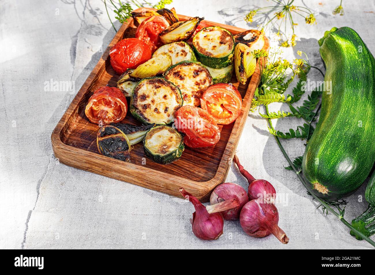 Zucchine grigliate, pomodori e cipolle dolci su un piatto di legno. Kebab di verdure. Verdure biologiche alla griglia. Verdure cotte e salsa. Cibo ancora Foto Stock