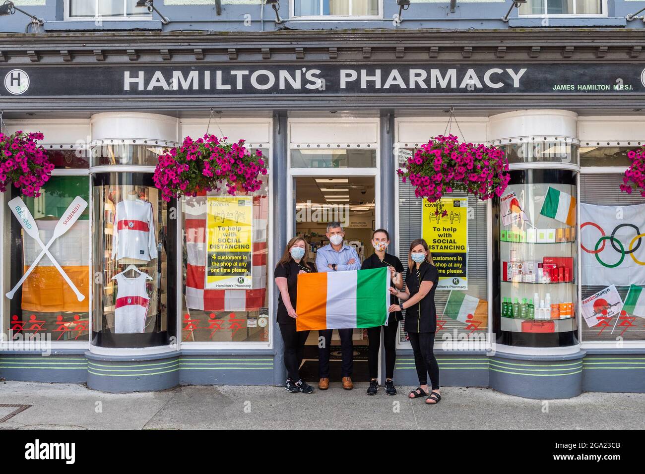 Skibbereen, West Cork, Irlanda. 28 luglio 2021. La gente della città di Skibbereen si stava preparando oggi a sostenere i vogatori irlandesi che gareggiavano nella finale Mens Lightweight Double sculls di domani mattina. I vogatori Fintan McCarthy e Paul o'Donovan di Skibbereen vanno in oro alle 1.50. Di fronte al negozio decorato per le Olimpiadi, la farmacia di Hamilton, sono stati raffigurati Stephanie Cronin; James Hamilton; Sharon Roycroft e Amy Minihane. Credit: AG News/Alamy Live News Foto Stock