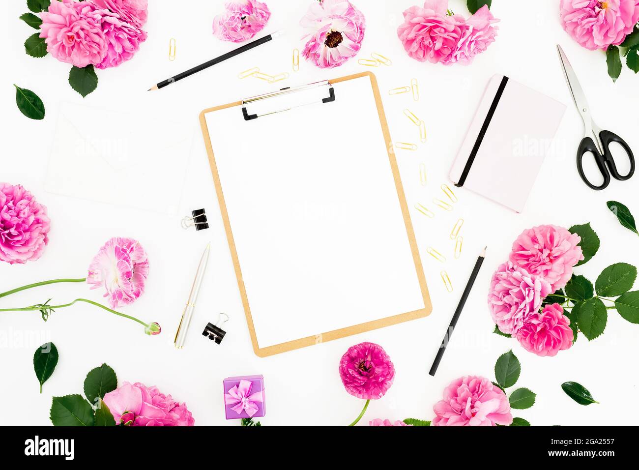 Luogo di lavoro piatto con portadocumenti, fiori rosa e accessori su sfondo bianco. Disposizione piatta, vista dall'alto. Foto Stock