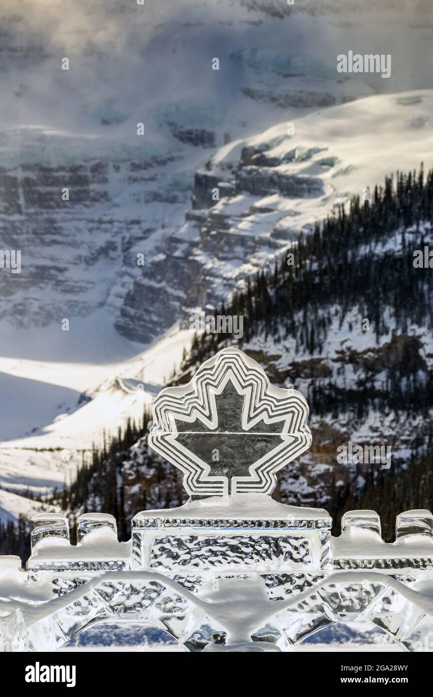 Sculture di ghiaccio Canadian Maple Leaf con sfondo di una montagna innevata nel Parco Nazionale di Banff; Lake Louise, Alberta, Canada Foto Stock