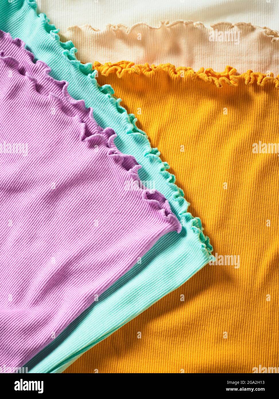 Capi di abbigliamento colorati con finiture in volant in un mucchio; studio Foto Stock