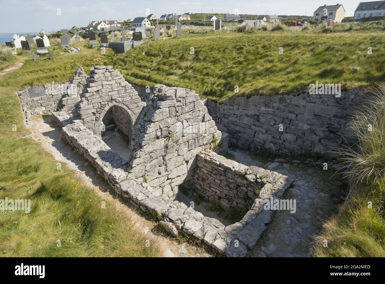 Rovine storiche di pietra della Chiesa di Saint Caomhan (Sunken Church) sulla collina erbosa su Iniseer, (Inis Oirr); Isole Aran, Contea di Galway, Irlanda Foto Stock