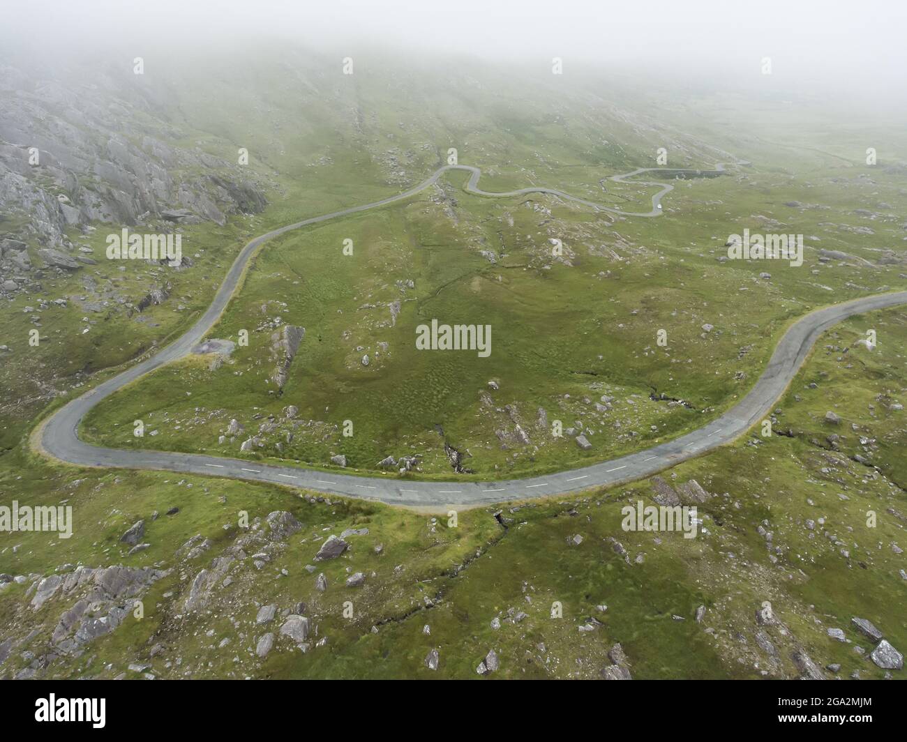 Vista aerea di un'auto che percorre la ventosa strada regionale irlandese nota come Healy Pass (R574); County Cork, Irlanda Foto Stock