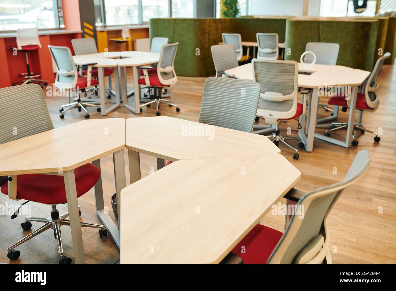 Interno di un grande ufficio open space contemporaneo con molte sedie da tavoli e lungo windowsills senza lavoratori o dirigenti intorno Foto Stock