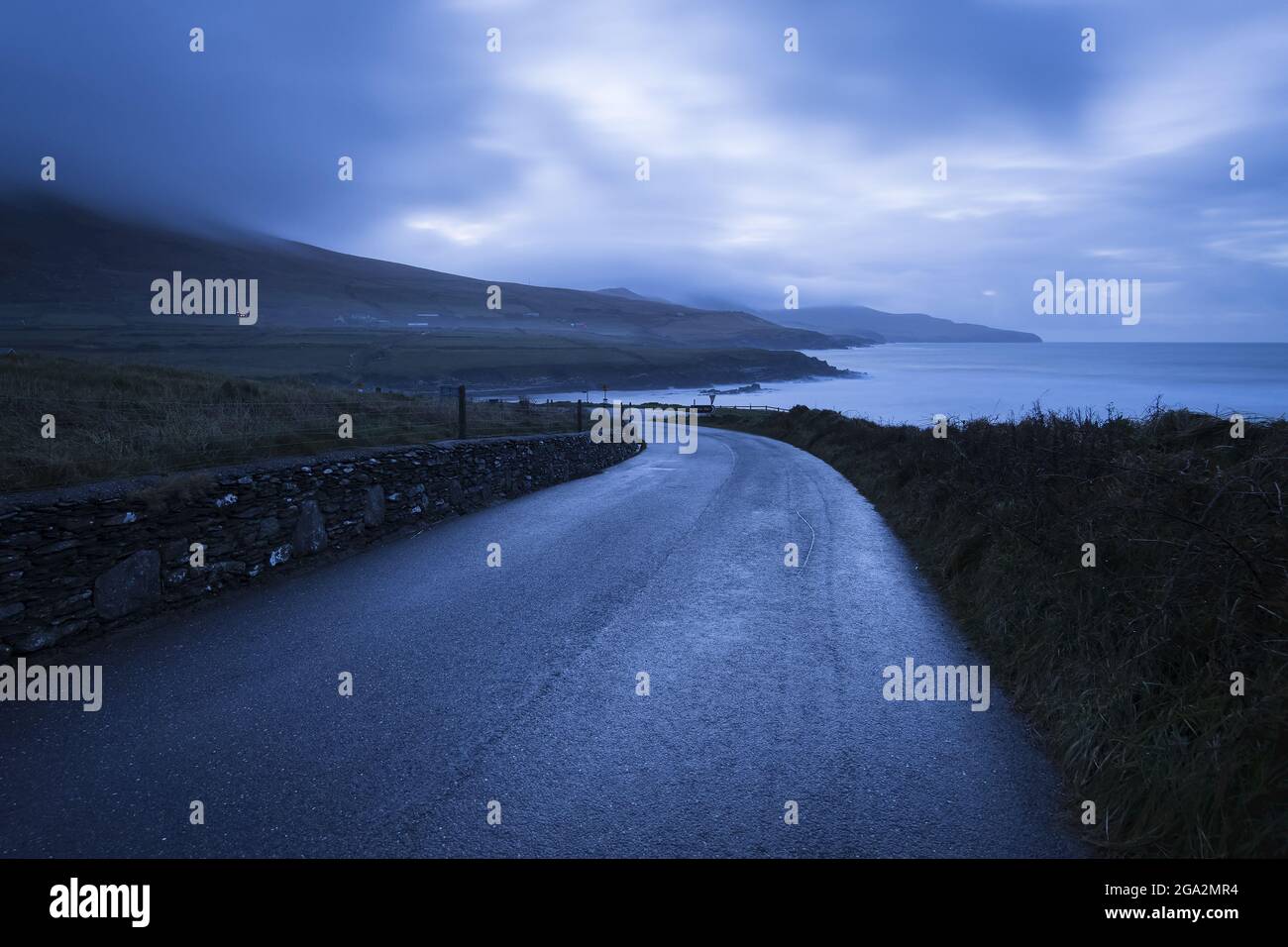 Viaggio panoramico lungo la strada costiera di St Finian's Bay (The Glen) al tramonto; County Kerry, Irlanda Foto Stock