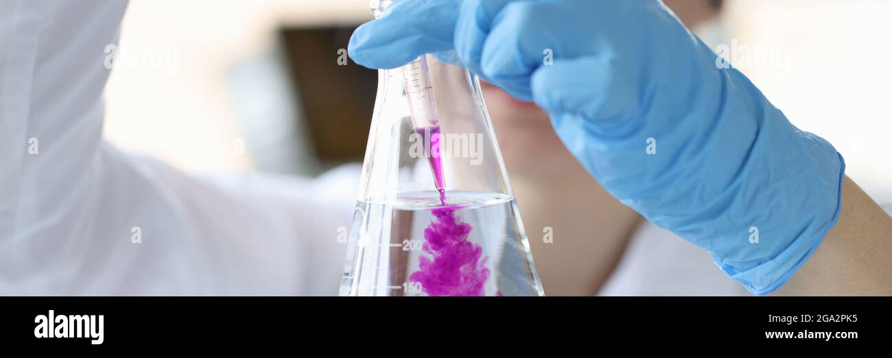 Chimico scienziato aggiungendo reagente al pallone di vetro con closeup dell'acqua Foto Stock