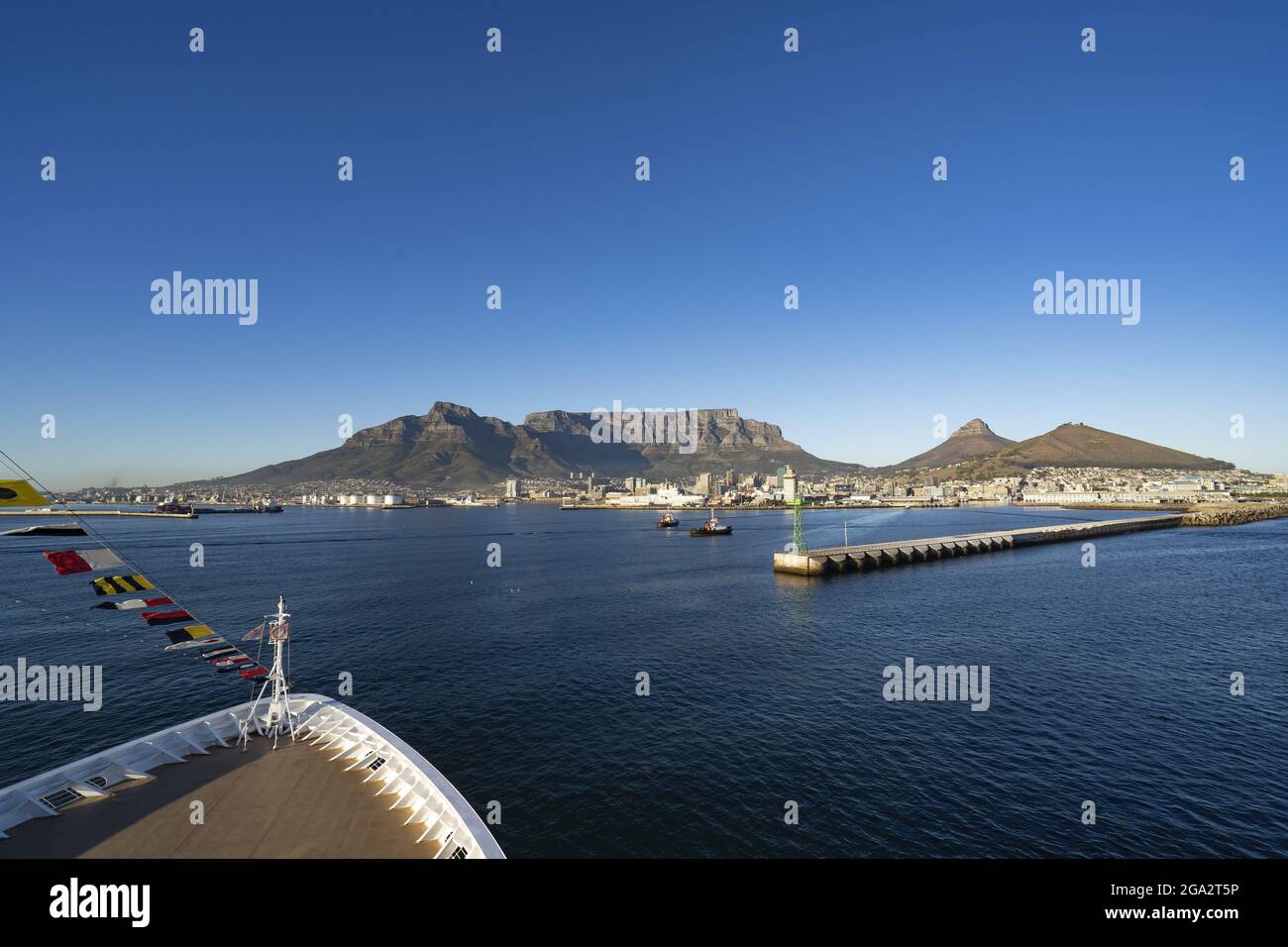 Primo piano dell'arco di una nave a Table Bay guardando verso il porto di Città del Capo e il maestoso Devil's Peak, Table Mountain e Lion's Head Risin... Foto Stock